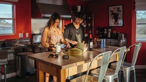 Uma cozinha moderna com eletrodomésticos de aço inoxidável, uma ilha de madeira e uma parede com detalhe em vermelho.