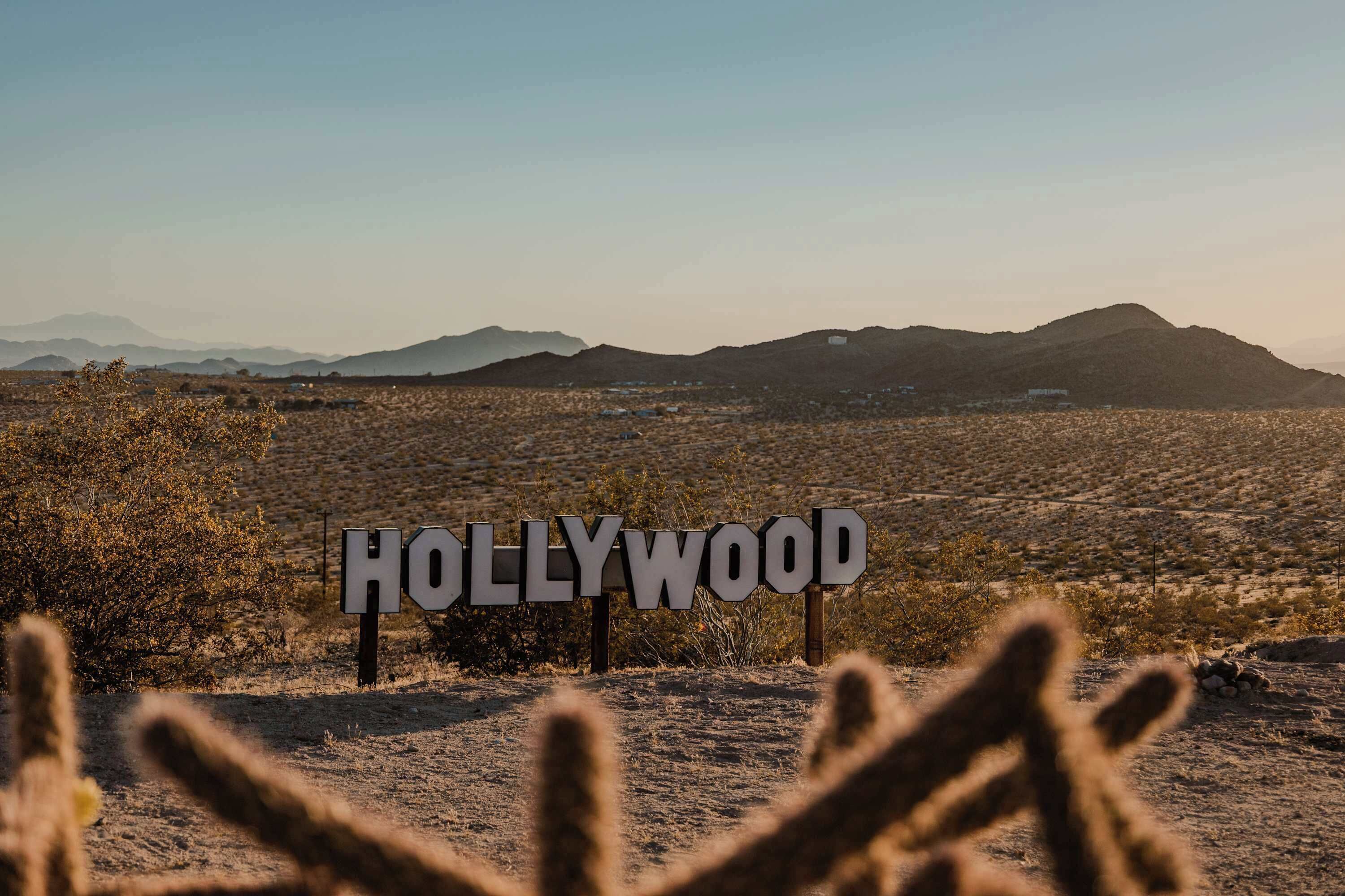 Paisagem desértica com uma placa indicando 'HOLLYWOOD' em primeiro plano.