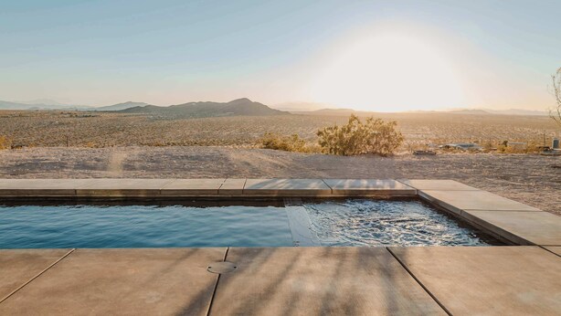 Piscina com vista para uma paisagem desértica e montanhas ao longe.