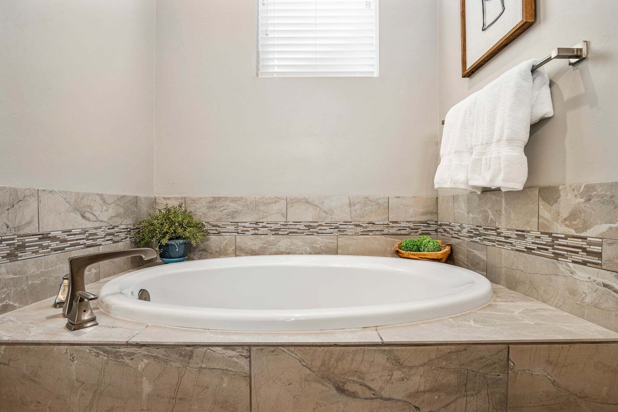 A bathroom with a freestanding bathtub, a small potted plant, and a towel rack.