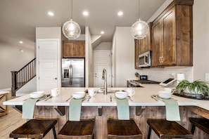 A modern kitchen with a central island, wooden cabinets, stainless steel appliances, and pendant lighting. - Ocotillo Springs 53, Private Pool, Spa, Resort Amenities (Santa Clara)