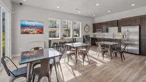 A modern kitchen with a stainless steel refrigerator, wooden cabinets, and a dining area with glass tables and chairs. - Ocotillo Springs 53, Private Pool, Spa, Resort Amenities (Santa Clara)