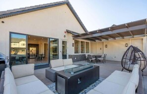 Eine moderne Außenpatio mit Glasveranda, bequemen Sitzgelegenheiten und einem Feuerbereich.