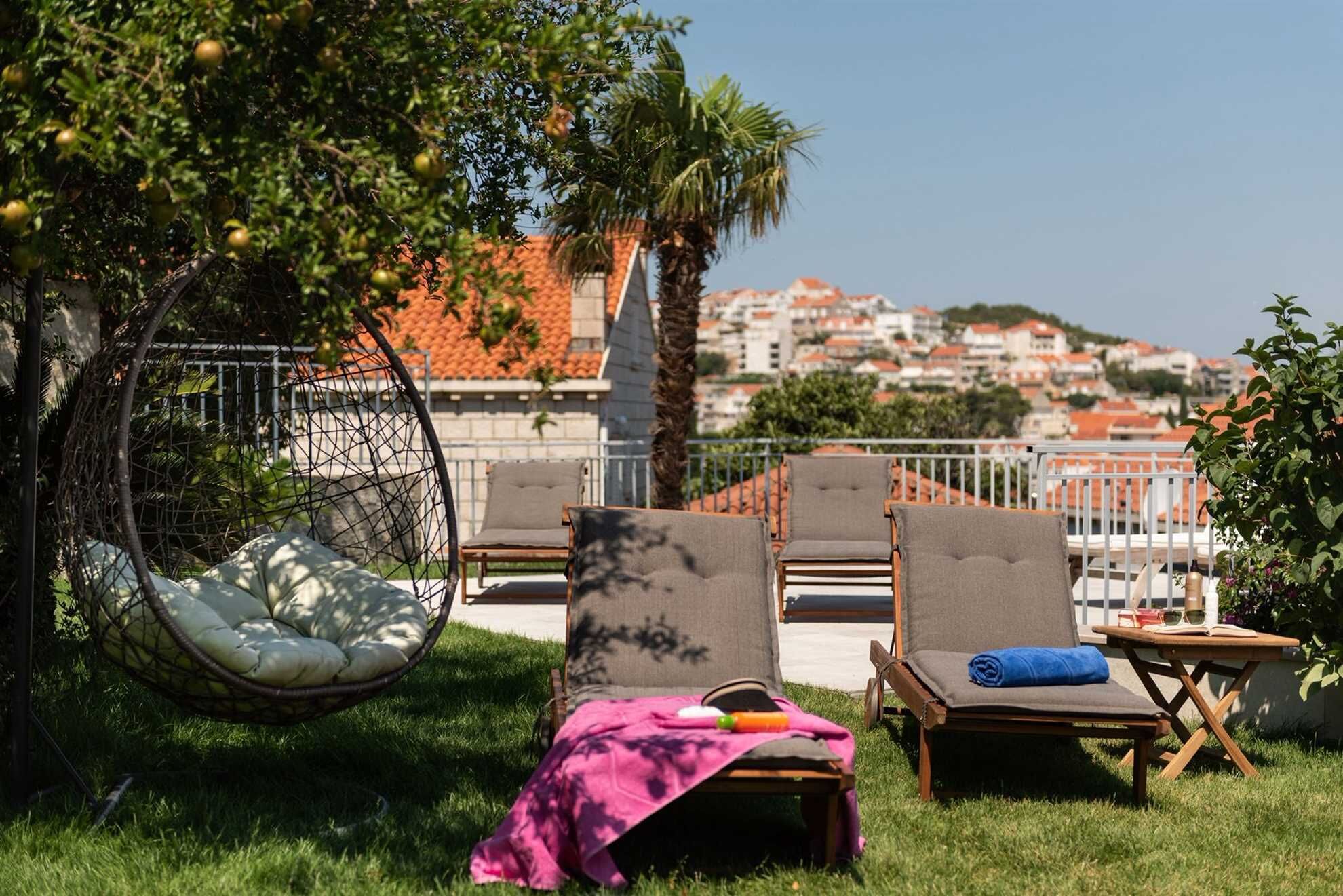 Eine Dachterrasse mit Sitzgelegenheiten im Freien, einer Hängematte und Blick auf eine Stadtlandschaft.