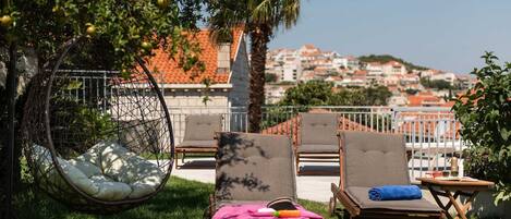 Eine Dachterrasse mit Sitzgelegenheiten im Freien, einer Hängematte und Blick auf eine Stadtlandschaft.
