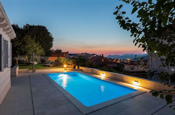 Ein Pool mit Blick auf eine Stadtlandschaft im Abendlicht.