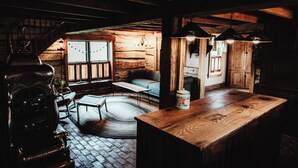 L’intérieur d’un chalet rustique en rondins de bois, avec un bar en bois, un coin salon et une cheminée.
