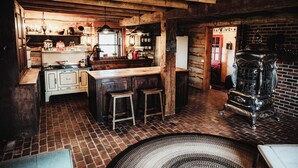 Une cuisine rustique avec un sol en briques, des armoires en bois, une grande cuisinière et un luminaire suspendu.
