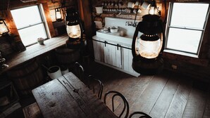 Une cuisine rustique avec des meubles de cuisine en bois, une table en bois et des lanternes suspendues.