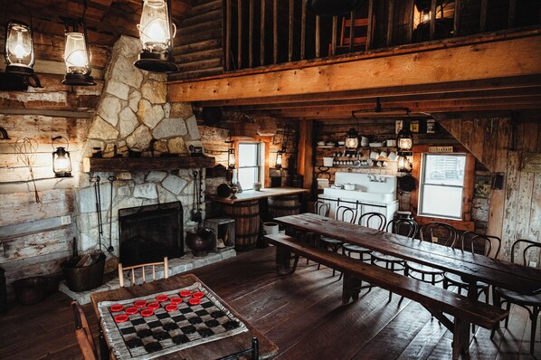 A rustic interior with a stone fireplace, wooden furniture, and vintage lighting fixtures.