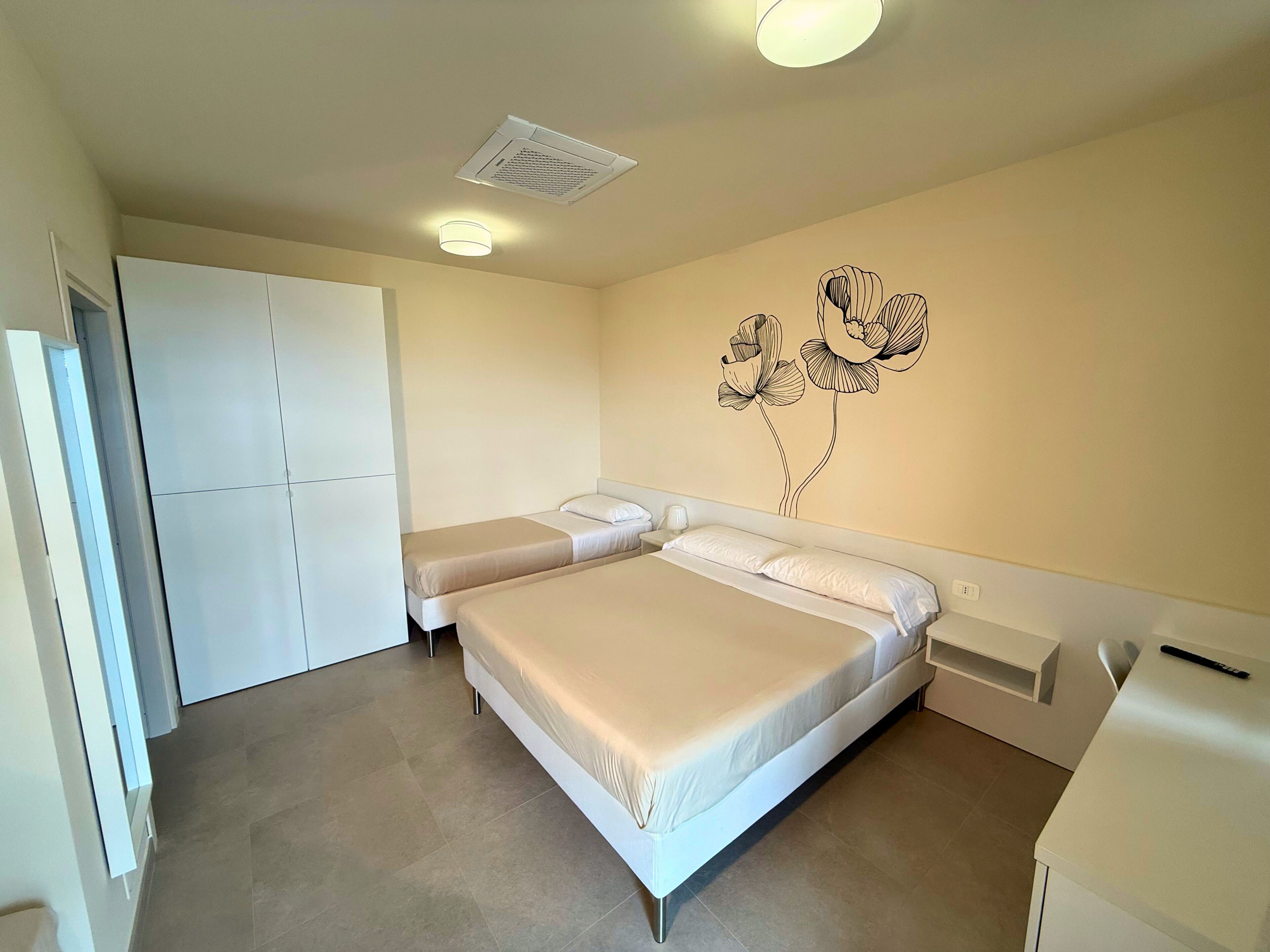 Une chambre à coucher comprenant un lit, une armoire, une bouche d’aération fixée au mur et un élément décoratif mural.