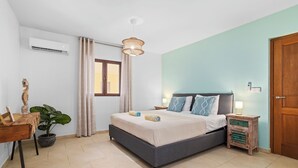 Ein Schlafzimmer mit Bett, Nachttischen, einer Topfpflanze und einem Fenster.