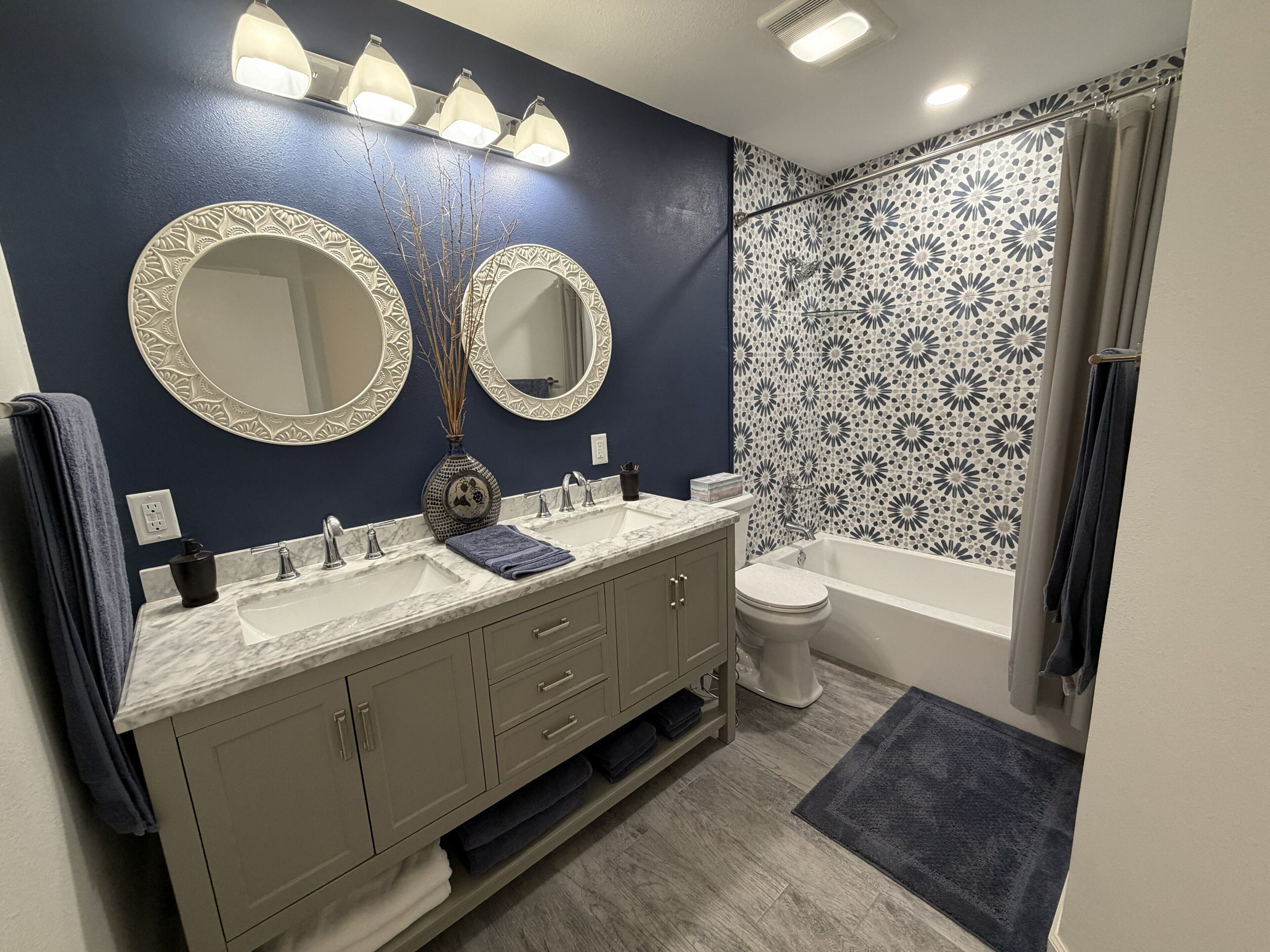 A bathroom with a double sink vanity, a toilet, a bathtub, and a shower area.