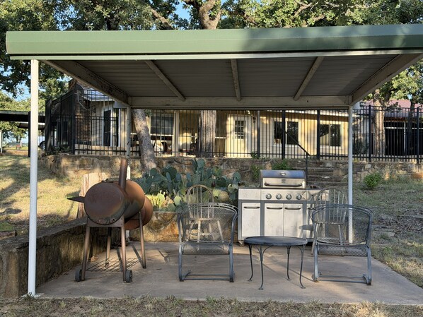 Une terrasse extérieure avec un barbecue, des chaises et un espace abrité.