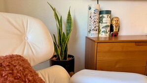 Ett rum med en vit soffa, en krukväxt, ett träskåp och en pusselbild som ligger på skåpet.