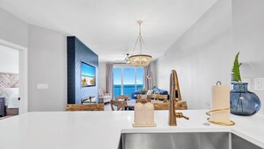 A modern kitchen with a large island, stainless steel sink, and a chandelier. - 5 Star Stays • Stocked Luxury Retreat • 2 Kg Suites (Panama City Beach)