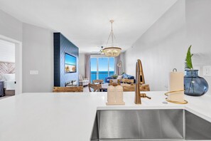 A modern kitchen with a large island, stainless steel sink, and a chandelier. - GulfFront Stocked Luxury Retreat • 2 King Suites (Panama City Beach)