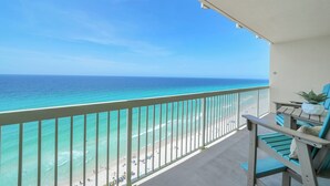 A balcony with a view of the ocean, a chair, and a small table. - 5 Star Stays • Stocked Luxury Retreat • 2 Kg Suites (Panama City Beach)