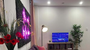 Una sala de estar moderna con sofá, televisión, lámpara y un elemento decorativo en la pared.
