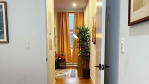 Un dormitorio con una cama, un pasillo que conduce a una sala de estar y una planta en maceta.