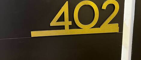 Een zwarte muur met een gouden bord met het cijfer '402'.