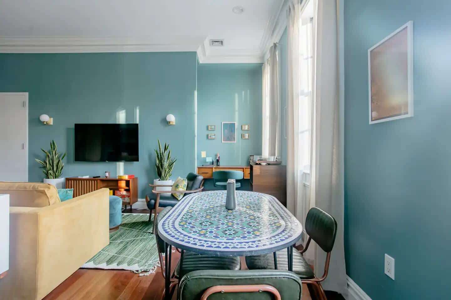 Una sala de estar con sofá, una mesa de centro, televisor y un comedor con sillas y una mesa.