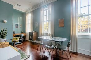 Una habitación con una mesa redonda, sillas, un sofá, un mueble bajo y una planta en maceta.