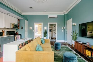 A living room with a sofa, ottoman, and a television.