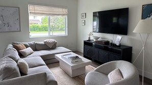 A modern living room with a sectional sofa, a coffee table, a round armchair, a TV, and a ceiling fan. - Beautiful home in the heart of Whitefish Montana (Whitefish)