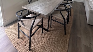 A dining area with a long wooden table, black chairs, a woven rug, and a hanging light fixture. - Beautiful home in the heart of Whitefish Montana (Whitefish)