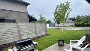 A patio with a grill, outdoor chairs, and a concrete deck. - Beautiful home in the heart of Whitefish Montana (Whitefish)