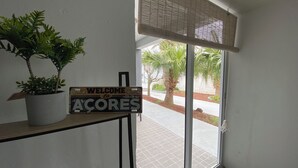 A welcome sign, a potted plant, and a view of palm trees through a window.