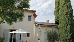 Une terrasse avec une table et des chaises, un parasol blanc et une plante en pot.