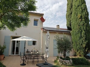 Eine Terrasse mit Tisch, Stühlen, einem weißen Sonnenschirm und einem Blumentopf.