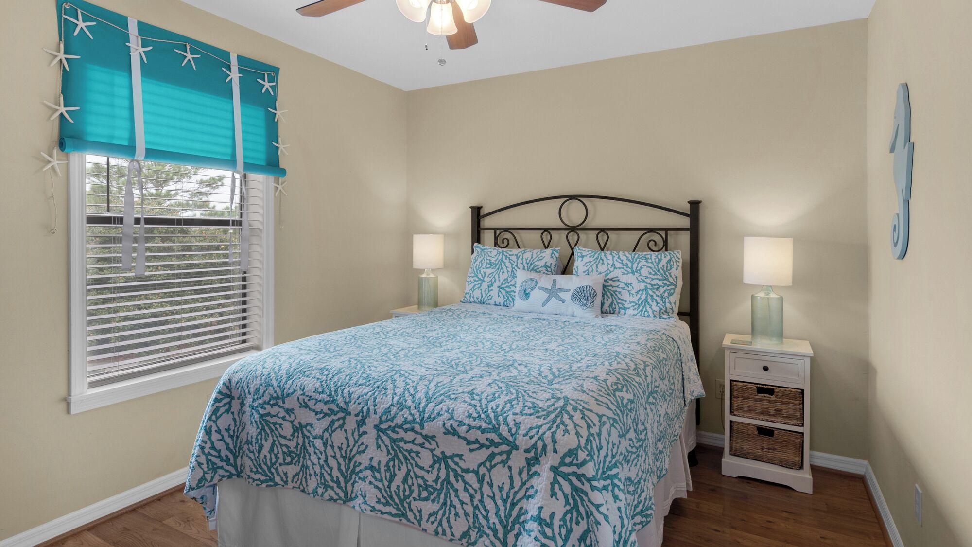 A bedroom with a bed, two bedside tables, a ceiling fan, and a window with blinds.