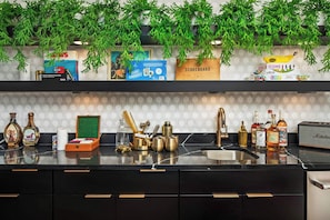 Uma cozinha moderna com bancada preta, puxadores dourados e diversos utensílios de cozinha e objetos decorativos.