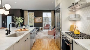 A modern kitchen with a central island, stainless steel appliances, and a view to a dining area. - Nashville home with skyline decks, media room, sleeps 12 (Nashville)