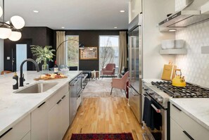 Cozinha moderna com ilha central, eletrodomésticos de aço inoxidável e vista para uma área de jantar.