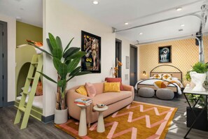 A modern living room with a sofa, a coffee table, and a large potted plant. - Downtown Nashville two-home rental with rooftop deck, sleeps 8 (Nashville)