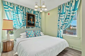 A bedroom with a bed, a nightstand, a lamp, a painting, and curtains. - Downtown Nashville two-home rental with rooftop deck, sleeps 8 (Nashville)