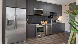 Una cucina moderna con elettrodomestici in acciaio inossidabile, mobili grigi e pavimento in legno.