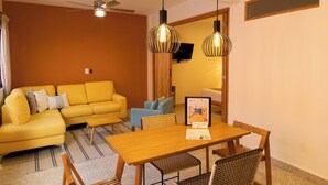 Sala de estar com sofá amarelo, mesa de jantar de madeira e luminárias pendentes.