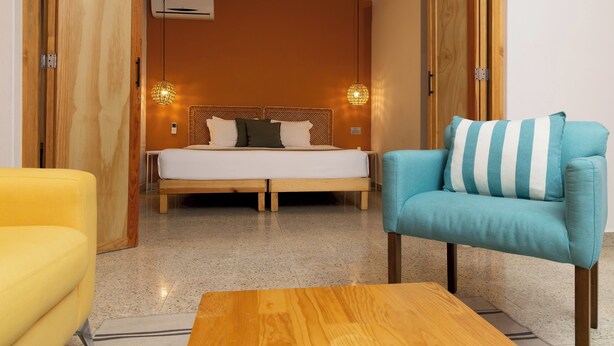Um quarto com cama, sofá, mesa de centro e porta de madeira.