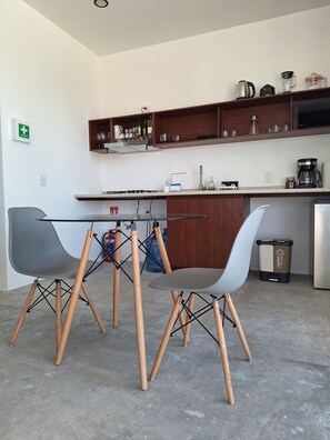 A modern kitchen with a dining area, including a table and chairs, a coffee maker, and a trash bin. - POSTAL 3 · Apt with garage and terrace w/views close downtown (Oaxaca)