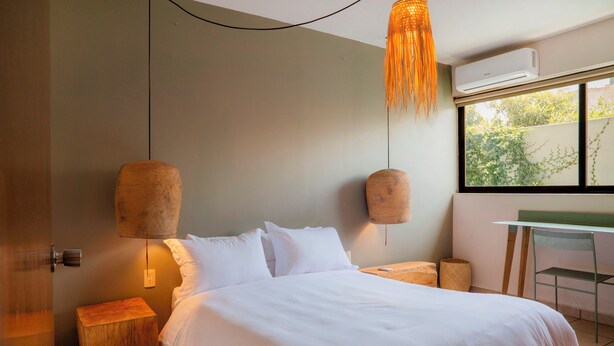 Une chambre moderne avec un grand lit, deux lampes fixées au mur, une petite table et une chaise.