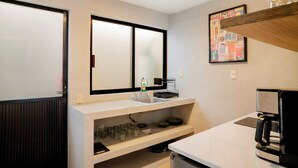 Une salle de bain moderne avec un grand miroir, un lavabo et une machine à café.