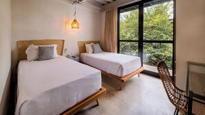 A room with two beds, a wooden chair, a desk, and a large window with a view of greenery. - GARCIA 3 · Spacious four Bedroom apt with Garden (Oaxaca)