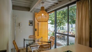 Ein modernes Interieur mit einem Glastisch, Korbstühlen, einer Pendelleuchte und Blick auf eine Terrasses.