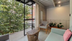 Ein Balkon mit Korbstuhl, Sofa und Topfpflanzen.