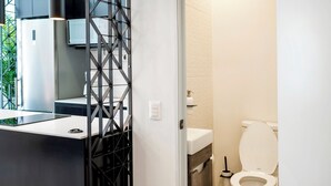 Een moderne badkamer met toilet, wastafel en een decoratieve zwarte scheidingswand.